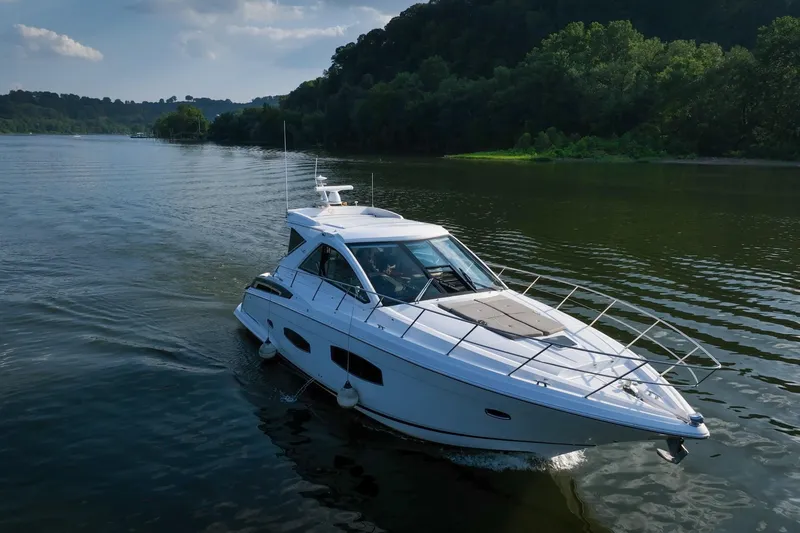 Slide: The Image of 2015 Regal 53 Sport Coupe cruising on a serene lake with lush green surroundings. - 3