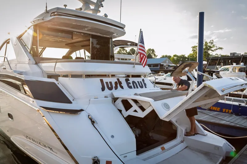Slide: The Image of 2015 Regal 53 Sport Coupe yacht docked, featuring "Just Enuf" name and American flag. - 55