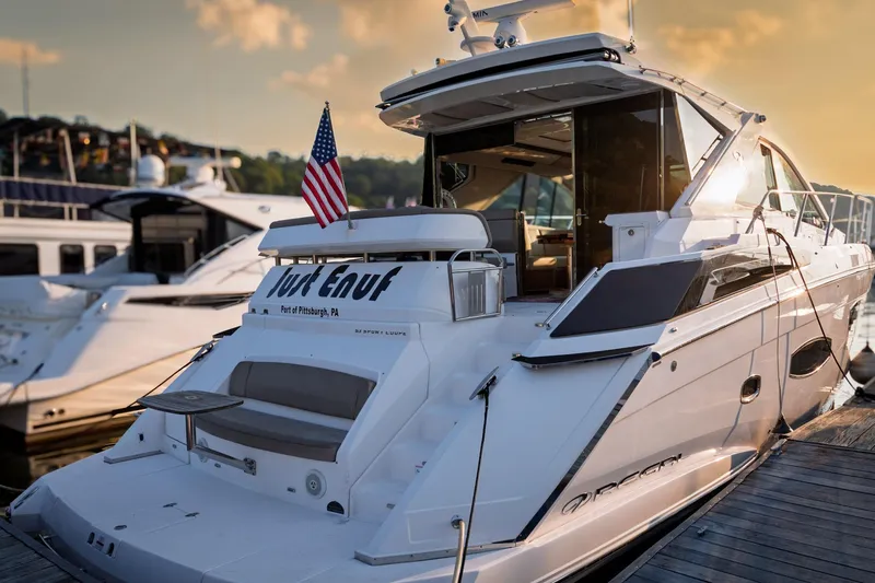 Slide: The Image of 2015 Regal 53 Sport Coupe yacht docked, featuring sleek design and American flag. - 61