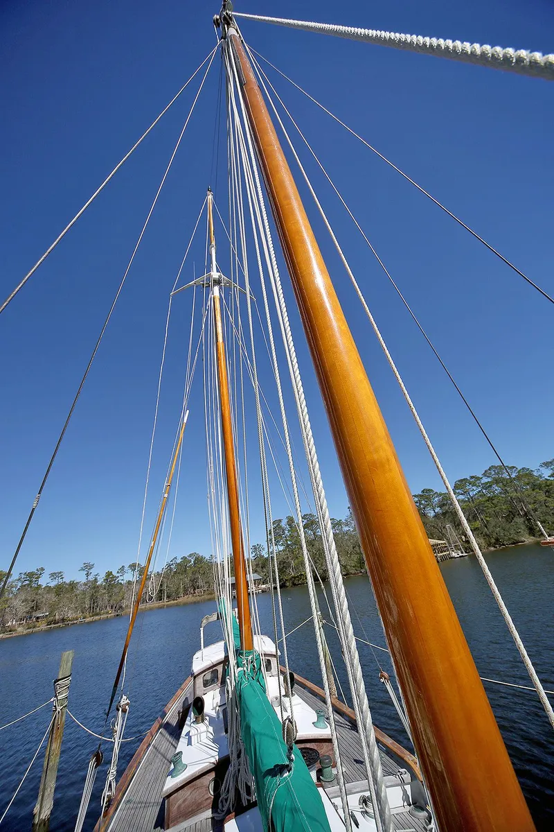 Slide: The Image of 1979 Custom Van Dyne Schooner with tall wooden masts on a serene lake. - 15