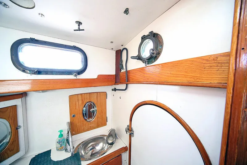 Slide: The Image of 1979 Custom Van Dyne Schooner bathroom with wooden accents and porthole windows. - 32
