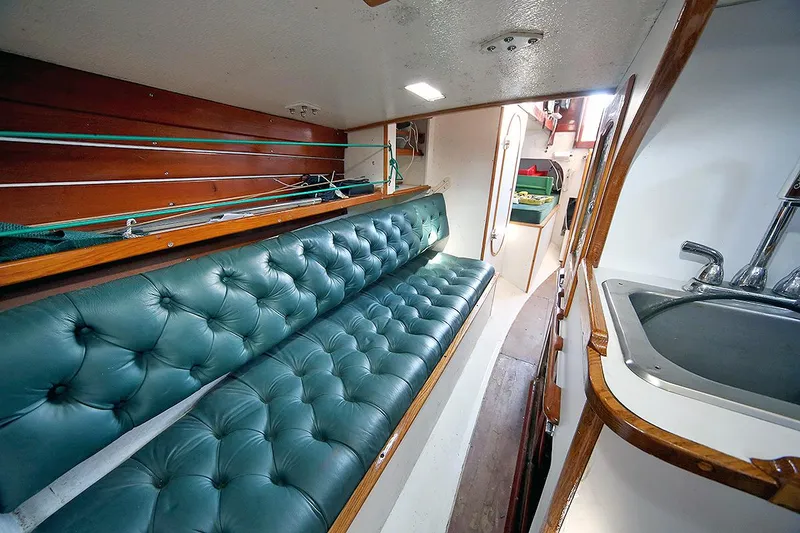 Slide: The Image of Interior of 1979 Custom Van Dyne Schooner with green tufted seating and compact kitchen area. - 39