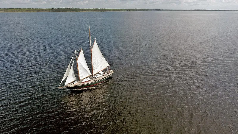 Slide: The Image of Aerial view of a 1979 Custom Van Dyne Schooner sailing on a vast, calm lake. - 5