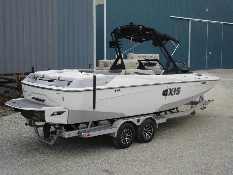 Slide: The Image of 2022 Axis A24 boat on trailer, white exterior, parked near a blue building. - 3