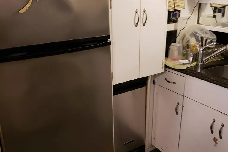 Slide: The Image of Small kitchen area inside a 1964 Chris-Craft Constellation boat, featuring cabinets and a sink. - 48