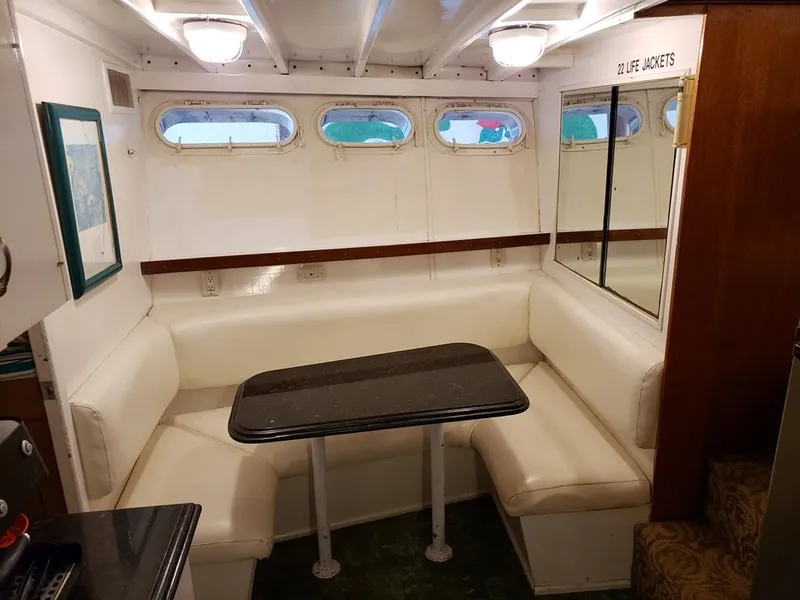 Slide: The Image of 1964 Chris-Craft Constellation interior with white seating and table, featuring porthole windows. - 33