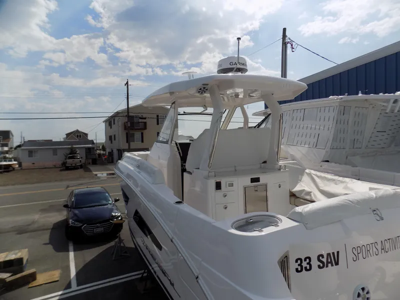 Slide: The Image of 2019 Regal 33 SAV boat docked, showcasing sleek design and modern features under a partly cloudy sky. - 15