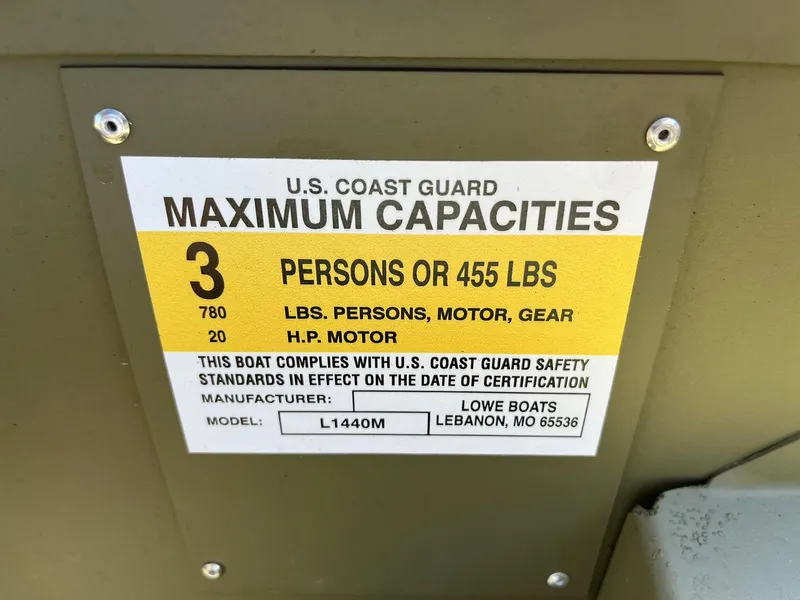 Slide: The Image of U.S. Coast Guard maximum capacities label on 2024 Lowe L1440M boat. - 7