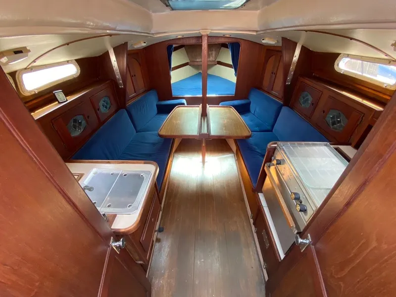 Slide: The Image of Interior of 1988 Newport 27 sailboat with wooden finish and blue seating. - 10