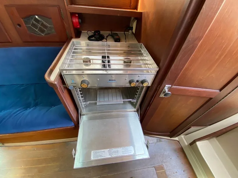 Slide: The Image of Compact kitchen area with a stainless steel stove and oven on a 1988 Newport 27 boat. - 11