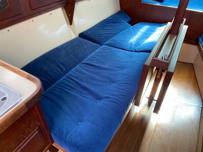 Slide: The Image of Interior of a 1988 Newport 27 sailboat with blue cushioned seating. - 13