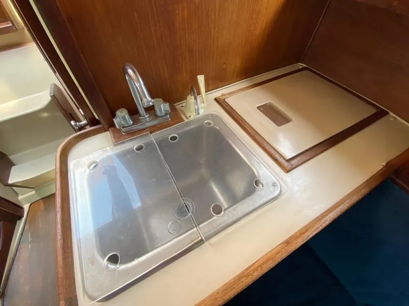 Slide: The Image of 1988 Newport 27 yacht kitchen sink with wooden cabinetry and stainless steel fixtures. - 15