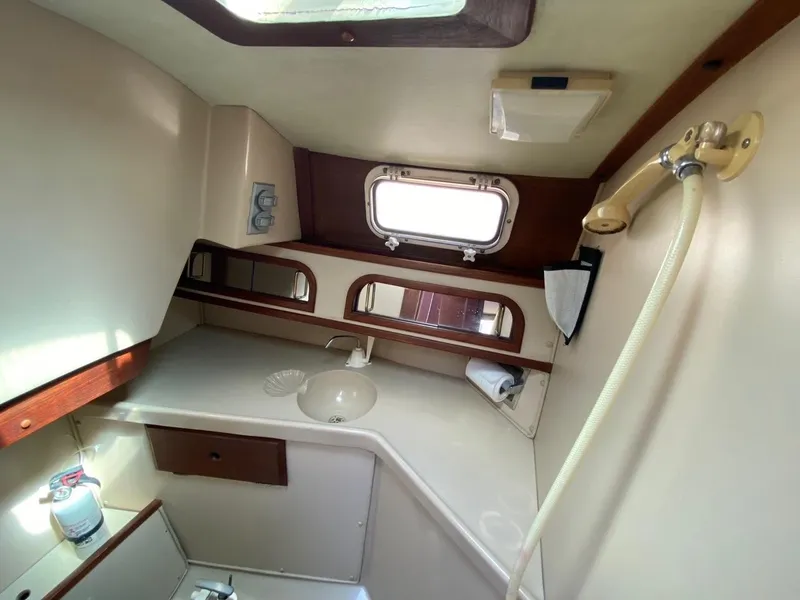 Slide: The Image of Interior of 1988 Newport 27 sailboat bathroom with sink, mirror, and porthole window. - 5