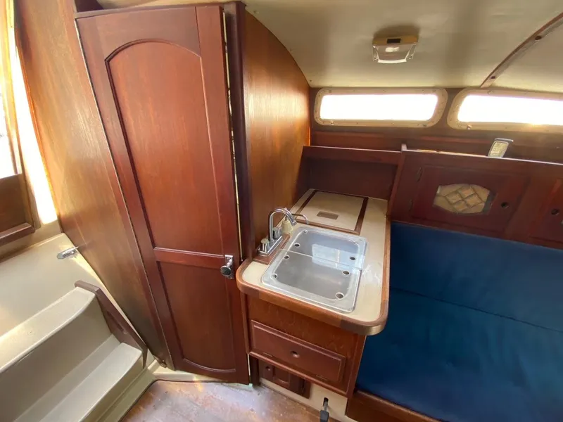 Slide: The Image of Interior of 1988 Newport 27 sailboat with wooden cabinetry and compact kitchen sink. - 8