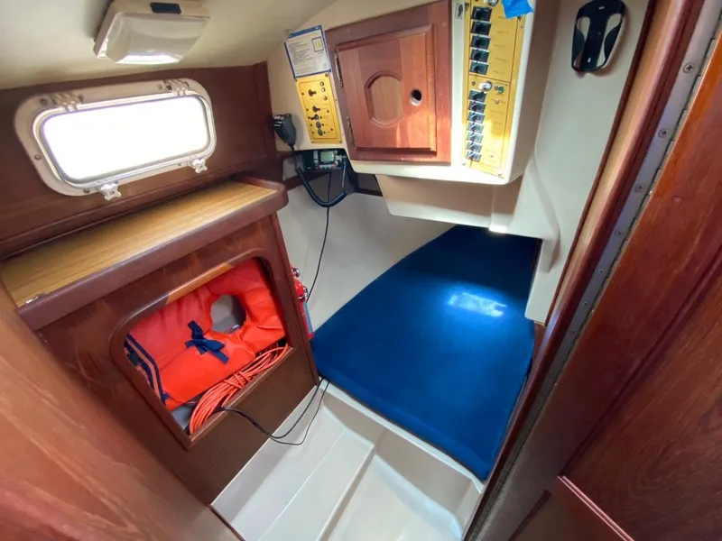 Slide: The Image of Interior of 1988 Newport 27 sailboat with wood paneling and blue flooring. - 9
