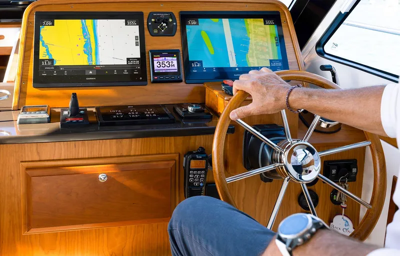 Slide: The Image of 2025 Back Cove 372 yacht helm with navigation screens and wooden steering wheel. - 14