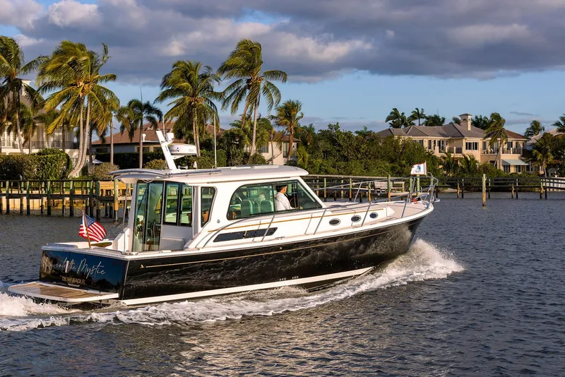 Slide: The Image of Back Cove 372 yacht cruising near waterfront homes, 2025 model. - 3