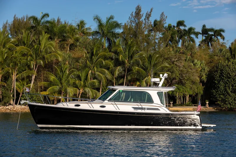 Slide: The Image of 2025 Back Cove 372 yacht cruising on a tropical waterway with palm trees in the background. - 8