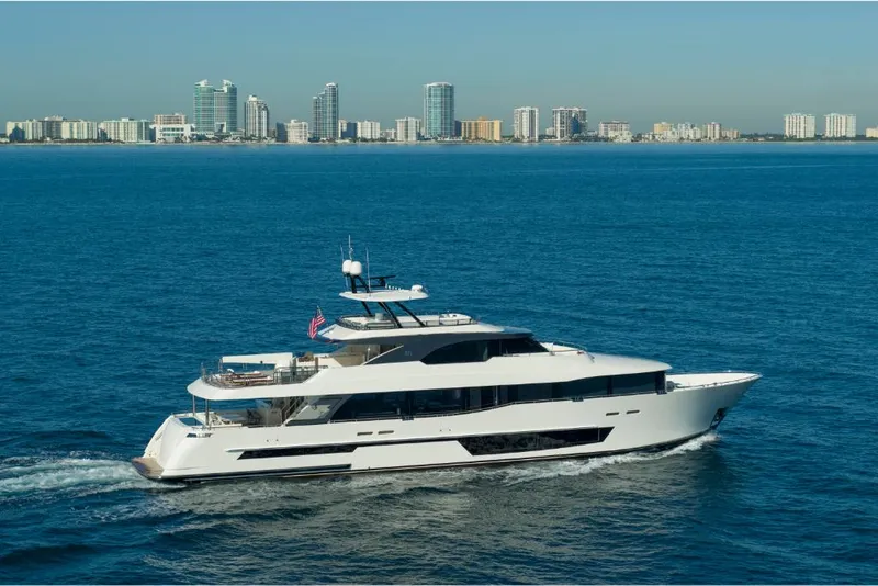 Slide: The Image of 2023 Ocean Alexander 37L yacht cruising near a coastal city skyline. - 2