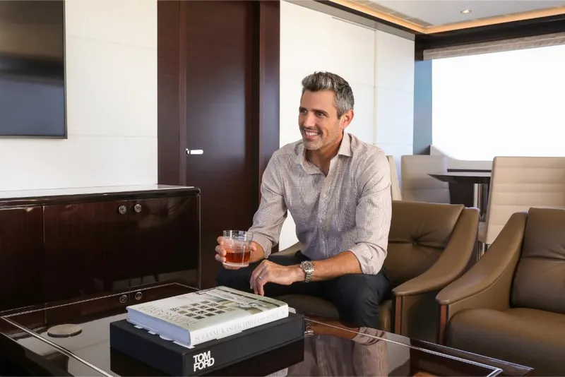 Slide: The Image of Man enjoying a drink in the luxurious interior of a 2023 Ocean Alexander 37L yacht. - 32