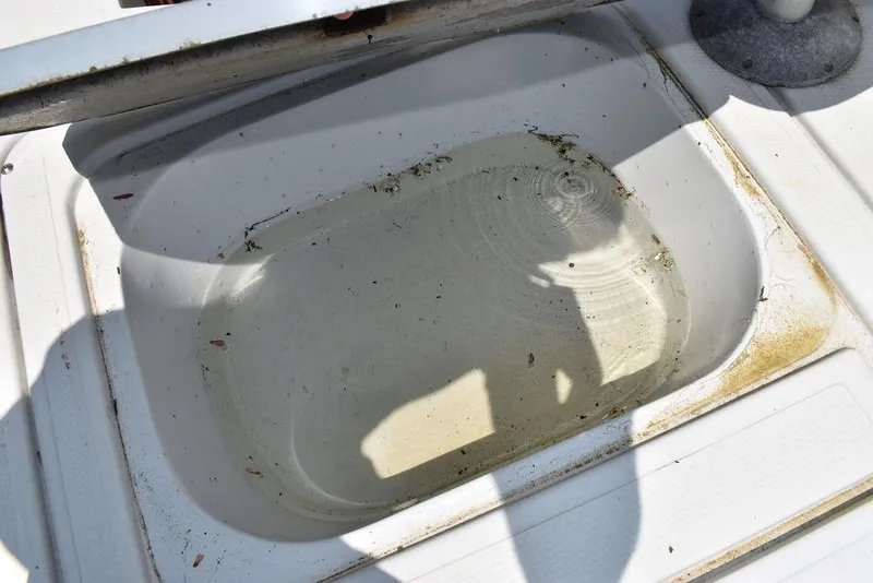 Slide: The Image of Open storage compartment on a 1991 Sea Sprite 225 boat with some water and debris. - 16