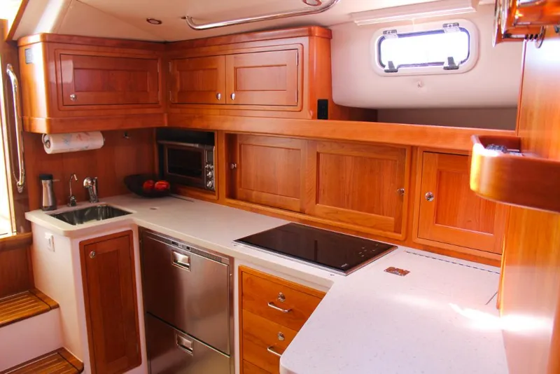 Slide: The Image of 2023 MJM 53z yacht kitchen with wooden cabinets, stainless steel appliances, and white countertops. - 19