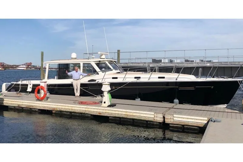Slide: The Image of 2023 MJM 53z yacht docked at a marina with a person standing on the deck. - 2