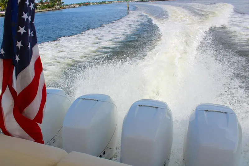 Slide: The Image of MJM 53z 2023 boat with four engines cruising on water, American flag waving. - 24