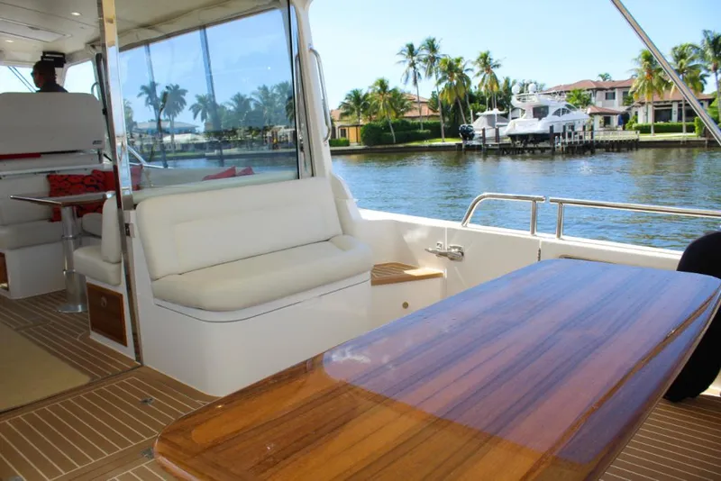 Slide: The Image of 2023 MJM 53z yacht interior with waterfront view, featuring white seating and wooden table. - 9
