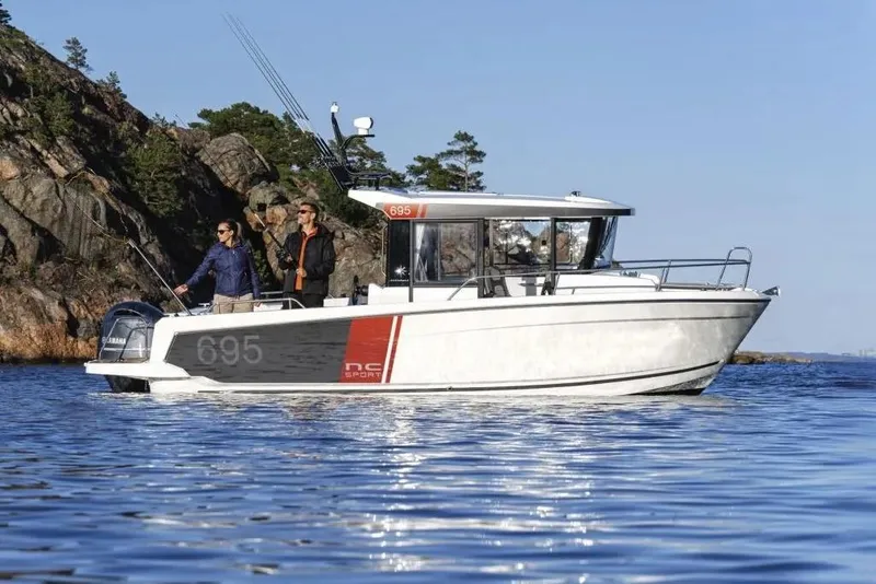 The Image of 2026 Jeanneau NC Sport 695 Series 2 boat cruising near rocky shoreline. - 0