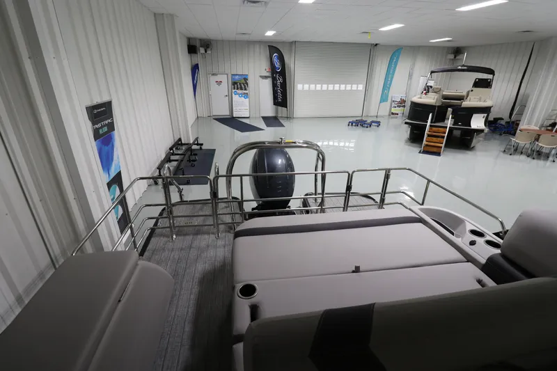 Slide: The Image of 2023 Sylvan L5 CLZ pontoon boat displayed in a showroom with banners and equipment. - 11