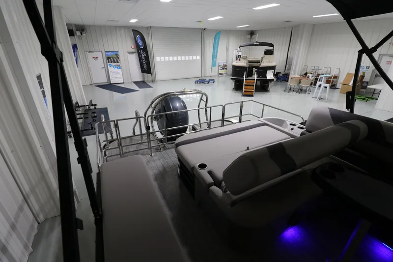 Slide: The Image of 2023 Sylvan L5 CLZ pontoon boat in showroom with modern seating and ambient lighting. - 12