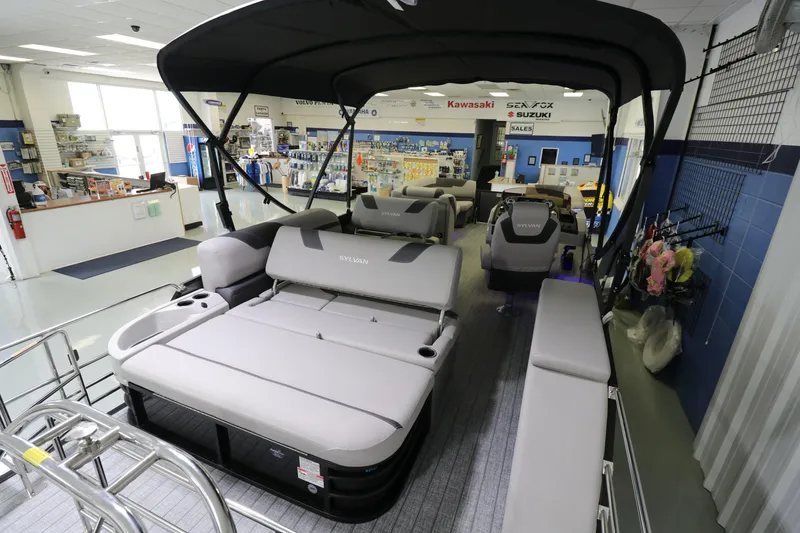Slide: The Image of 2023 Sylvan L5 CLZ pontoon boat displayed in a showroom with seating and canopy. - 8
