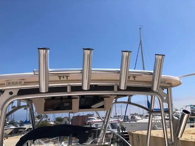 Slide: The Image of 2014 Grady-White Journey 258 boat with rod holders, docked at a marina under clear blue sky. - 10