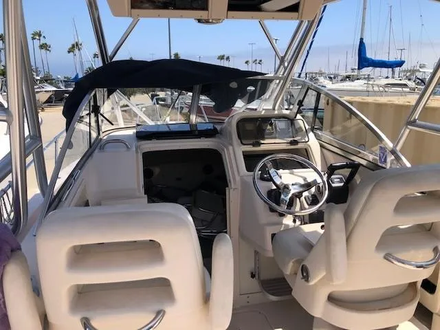 Slide: The Image of 2014 Grady-White Journey 258 boat interior with steering wheel and seating at marina. - 7