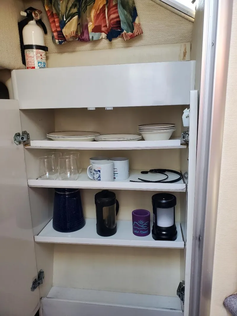 Slide: The Image of 1997 Chaparral Signature 29 boat interior kitchen shelves with dishes and appliances. - 12