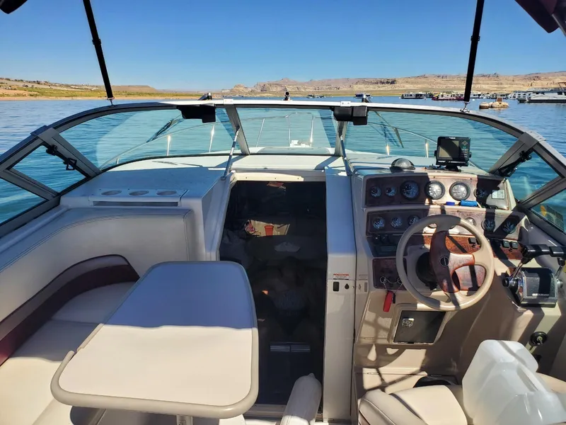 Slide: The Image of 1997 Chaparral Signature 29 boat interior with steering wheel and seating area on a lake. - 4