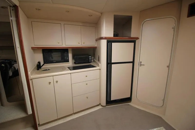 Slide: The Image of 2000 Cruisers Yachts 3870 Express interior kitchen with cabinets, sink, and refrigerator. - 19