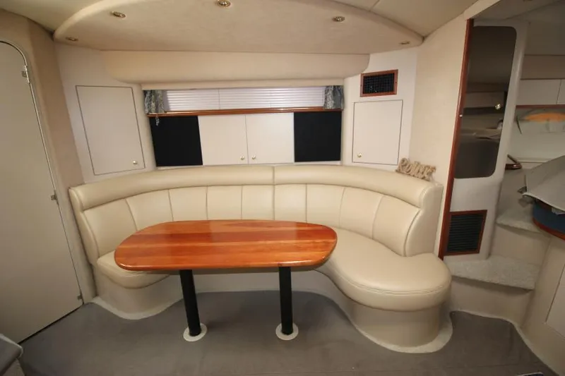 Slide: The Image of Interior of 2000 Cruisers Yachts 3870 Express with curved seating and wooden table. - 24