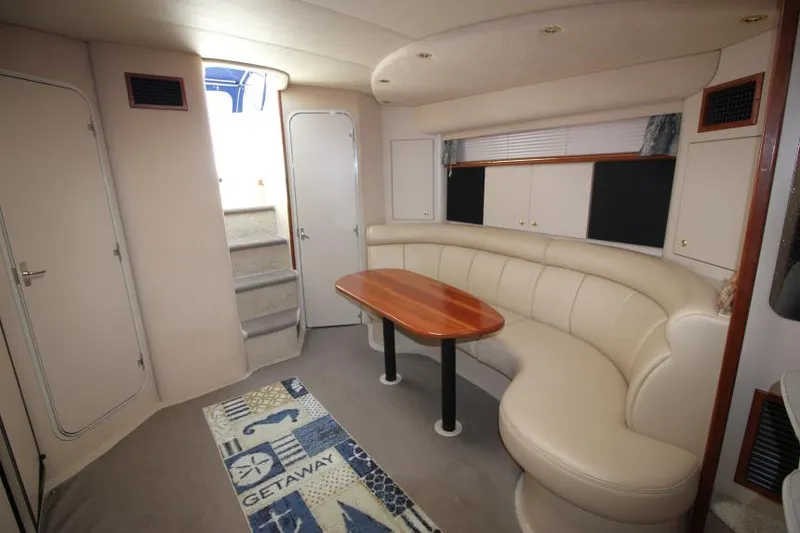 Slide: The Image of Interior of 2000 Cruisers Yachts 3870 Express with curved seating and wooden table. - 25