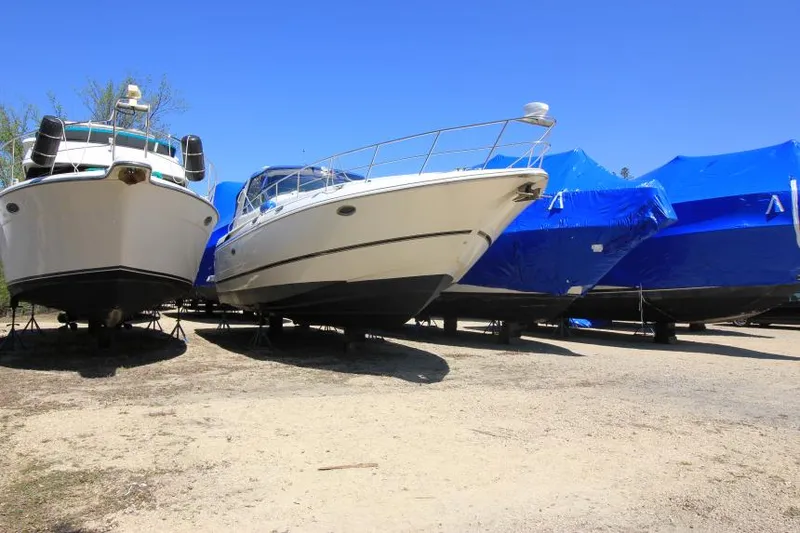 Slide: The Image of Boats in storage, including a 2000 Cruisers Yachts 3870 Express, under clear blue sky. - 3