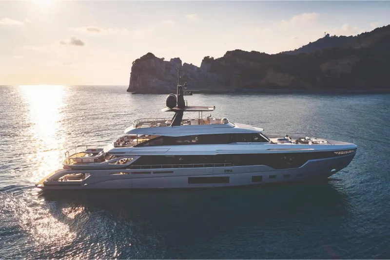 Slide: The Image of 2023 Azimut Trideck yacht cruising at sunset near rocky coastline. - 1