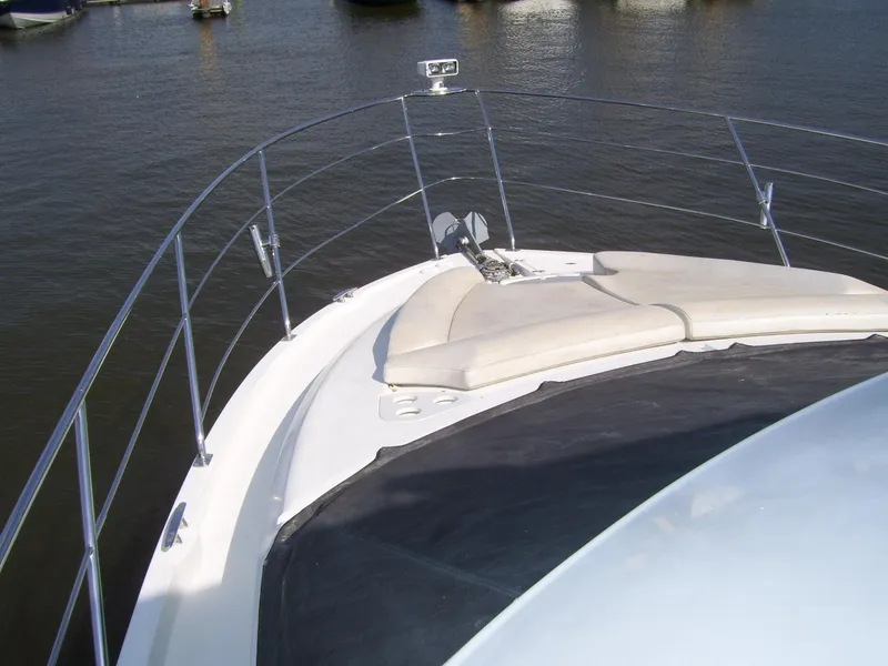 Slide: The Image of 2007 Carver 43 Motor Yacht bow with cushioned seating, anchored on calm water. - 4