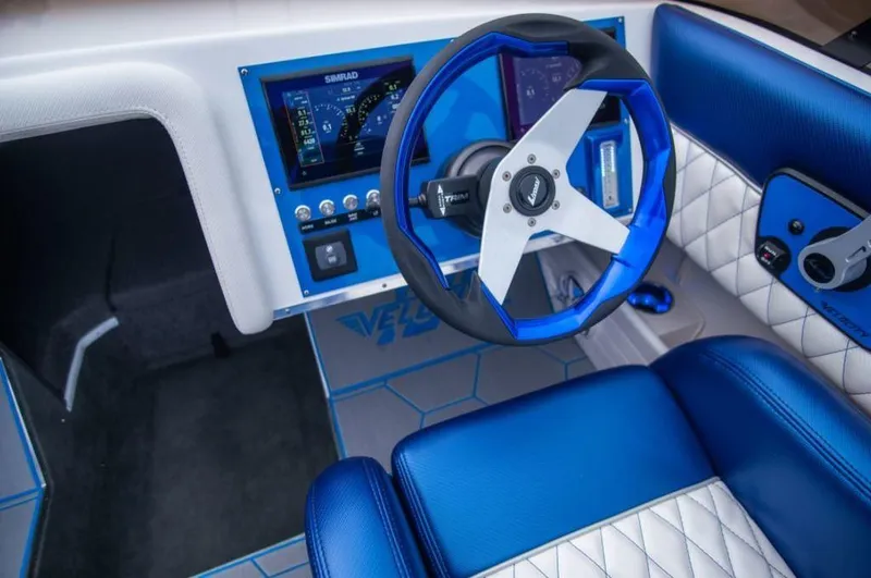 Slide: The Image of 2024 Velocity 230SC boat interior with blue and white upholstery and modern dashboard. - 3