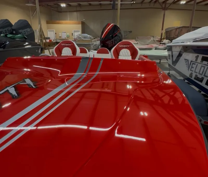 Slide: The Image of Red Velocity 22 Punisher boat, 2026 model, with sleek design and racing stripes in a showroom. - 10