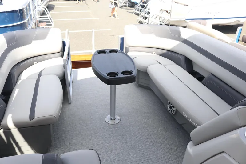 Slide: The Image of 2023 Sylvan L3 ENT pontoon boat interior with plush seating and a central table. - 12