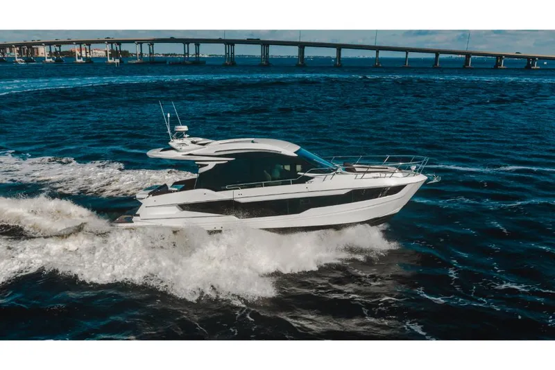 Slide: The Image of 2023 Galeon 410 HTC yacht cruising on open water near a bridge. - 14