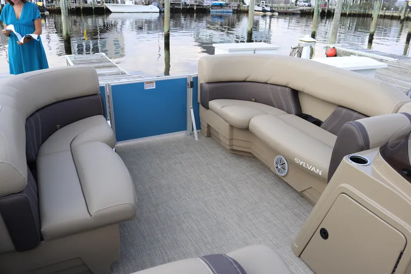 Slide: The Image of 2023 Sylvan Mirage 8520 Cruise pontoon boat interior with beige seating at a marina. - 18