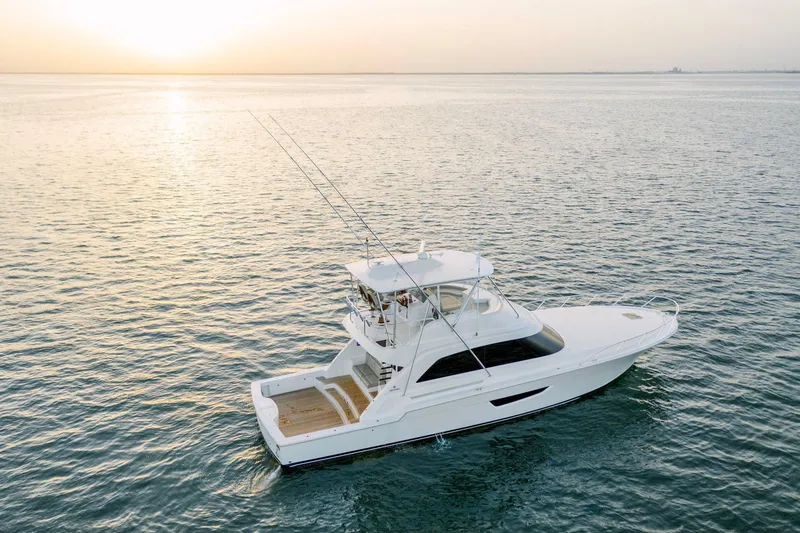 Slide: The Image of 2023 Bertram 61 Convertible yacht cruising at sunset on open water. - 1
