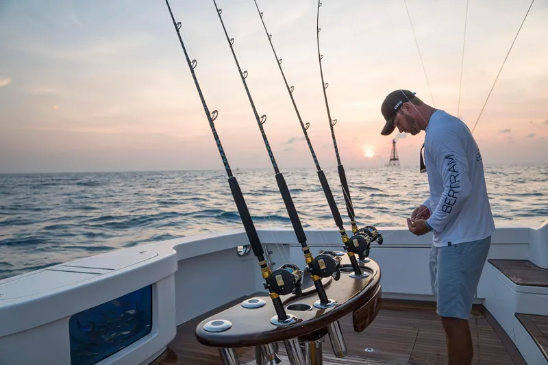 Slide: The Image of Man fishing on a 2023 Bertram 61 Convertible boat at sunset. - 15